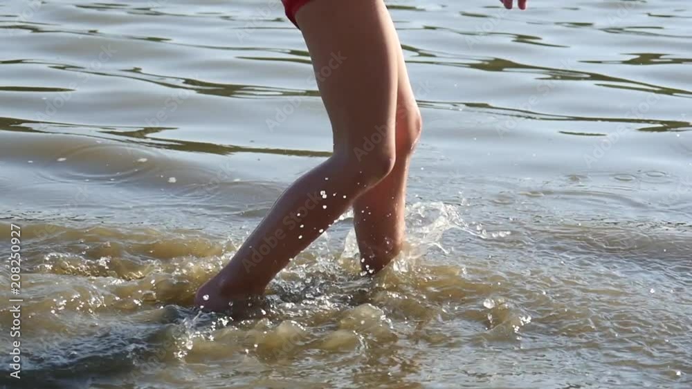 Lake beach rest little kid girl legs running in shallow water near shore in slow motion Lake beach rest little kid girl legs running in shallow water near shore in slow motion
