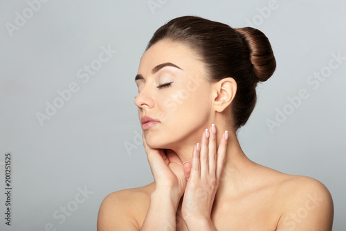 Beautiful young woman with silky skin after spa treatment on light background