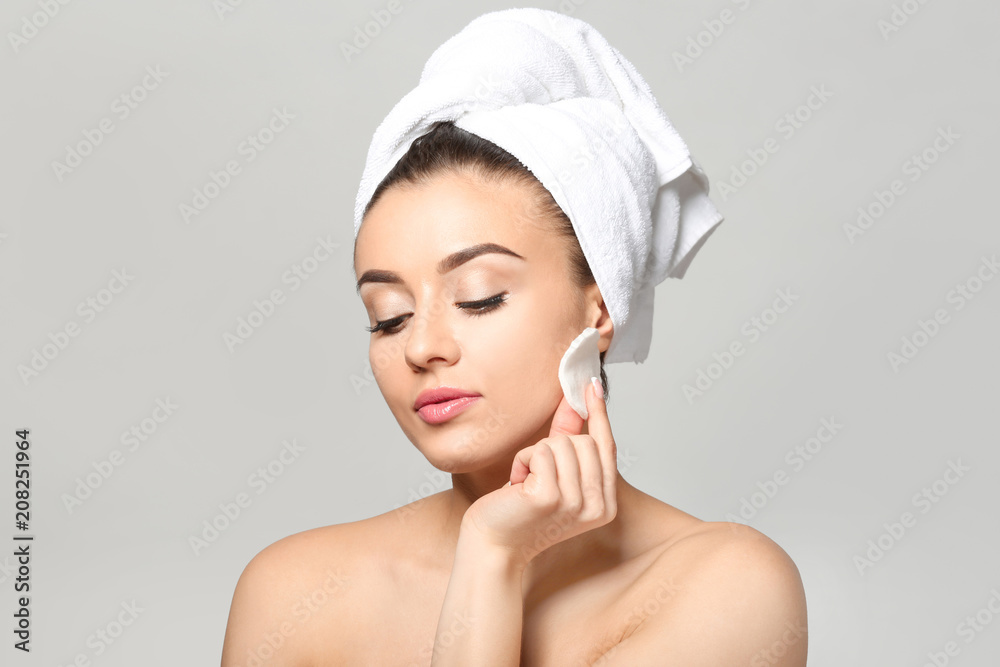 Beautiful young woman using cotton pad on light background Beautiful young woman using cotton pad on light background