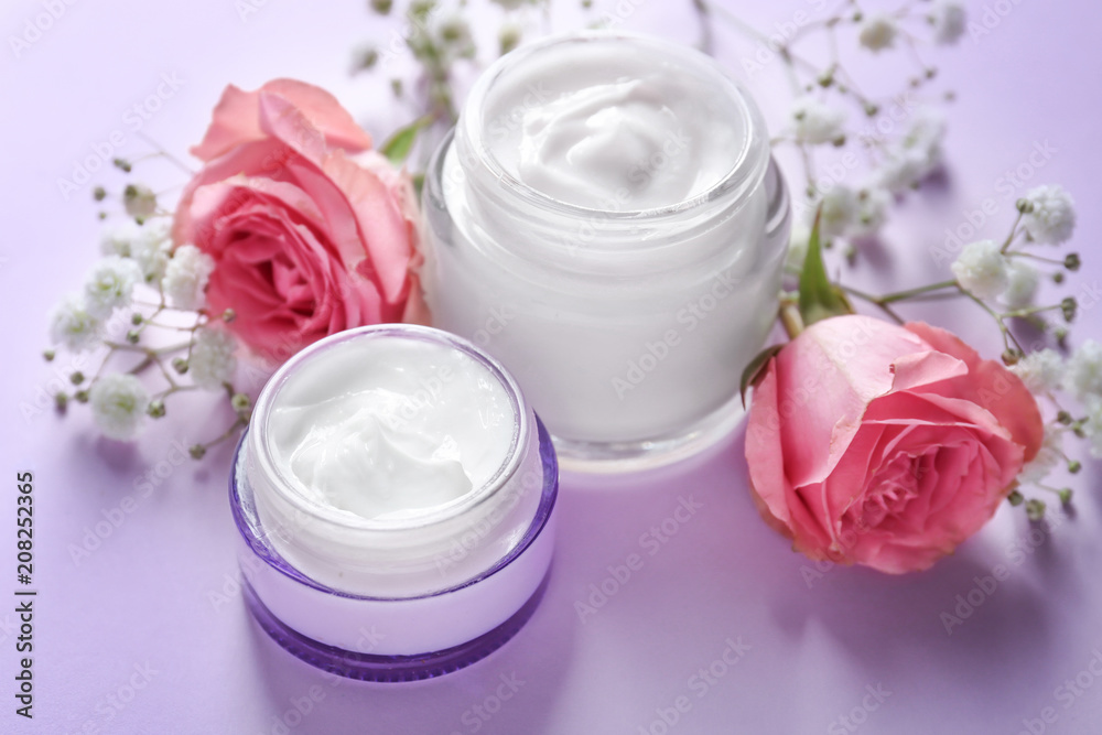 Beautiful composition with body cream and flowers on color background Beautiful composition with body cream and flowers on color background