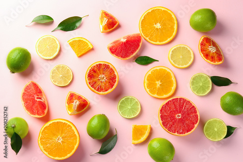 Different cut citrus fruits on color background  top view