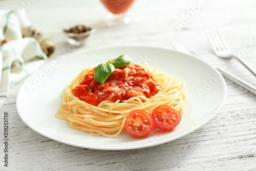 Plate of delicious pasta with tomato sauce on white wooden table
