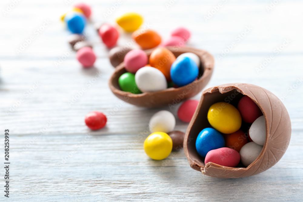 Chocolate Easter eggs with colorful candies on white wooden background Chocolate Easter eggs with colorful candies on white wooden background