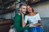 Two happy mixed race couple having fun at the coffee shop. Couple enjoying at a coffee shop, sitting at table and laughing.