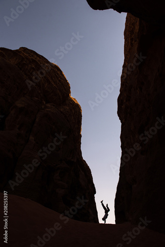 Woman doing a cart wheel in a narrow canyon