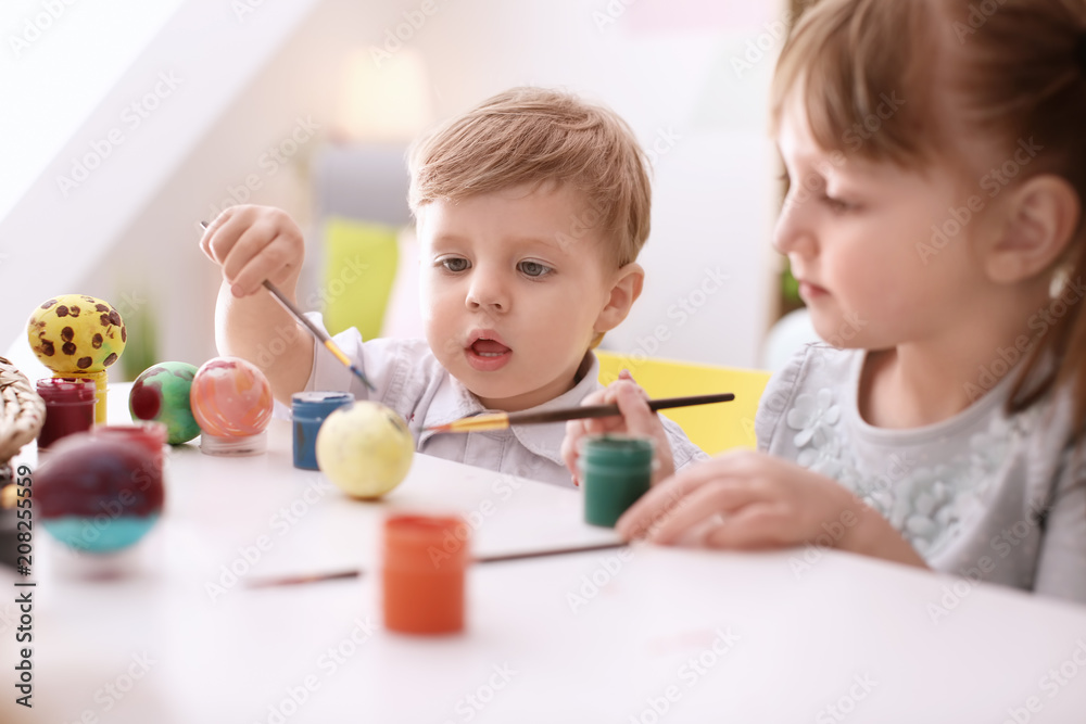 Cute kids painting Easter eggs together at table Cute kids painting Easter eggs together at table