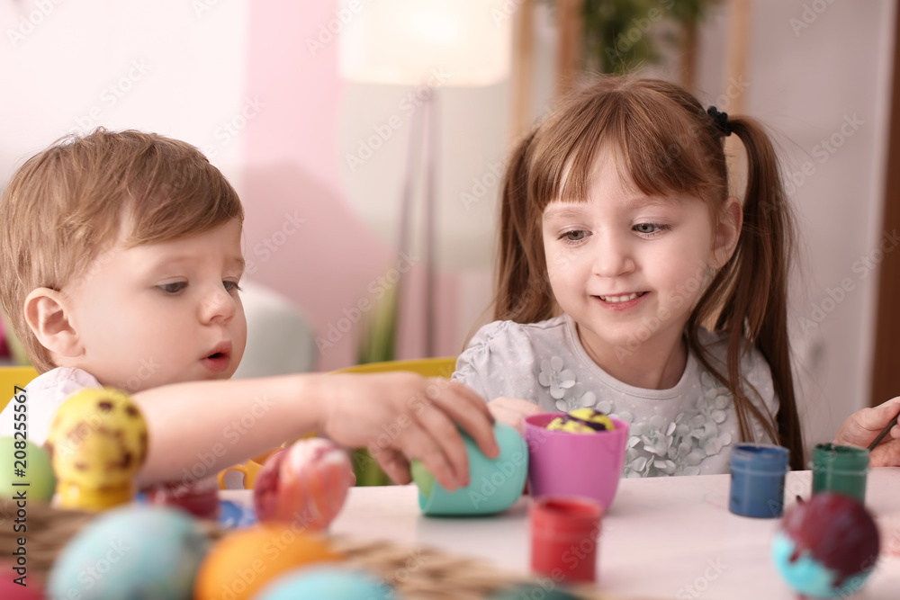 Cute kids painting Easter eggs together at table Cute kids painting Easter eggs together at table