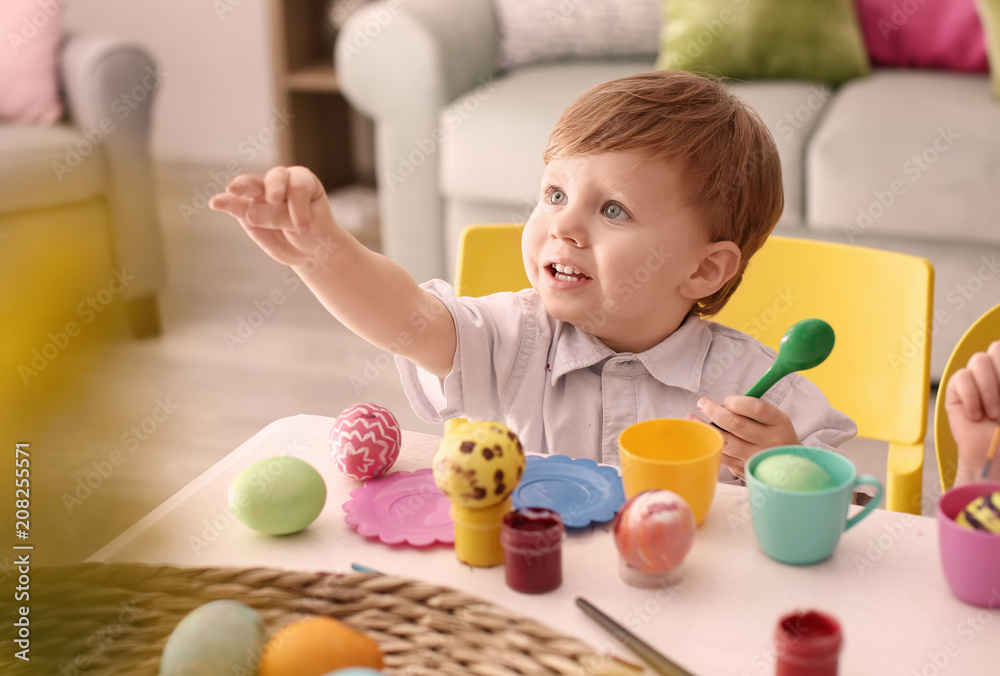 Cute little boy painting Easter eggs at table Cute little boy painting Easter eggs at table