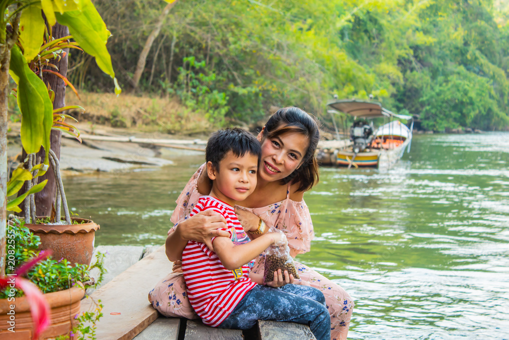 Mother and son sit to feed the fish Stock Photo | Adobe Stock