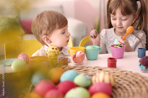 Cute kids painting Easter eggs together at table