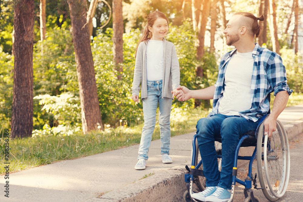 Best friends. Happy cheerful delighted girl smiling and holding a hand of her father while having a walk with him Best friends. Happy cheerful delighted girl smiling and holding a hand of her father while having a walk with him