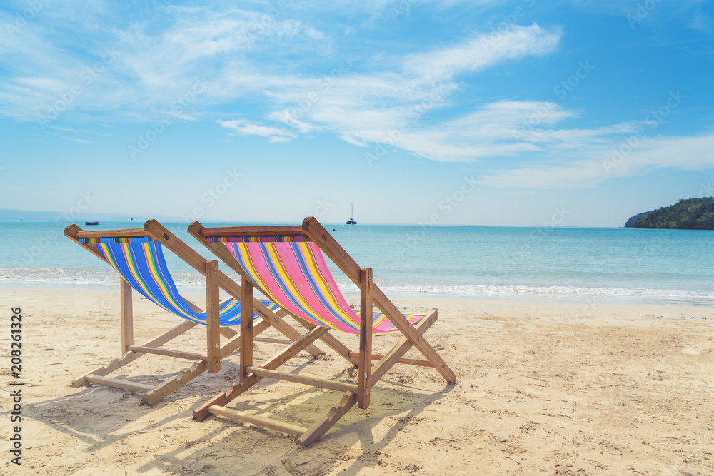 Two beach chairs on the white sand with blue sky and summer sea background. Summer, Vacation, Travel and Holiday concept.