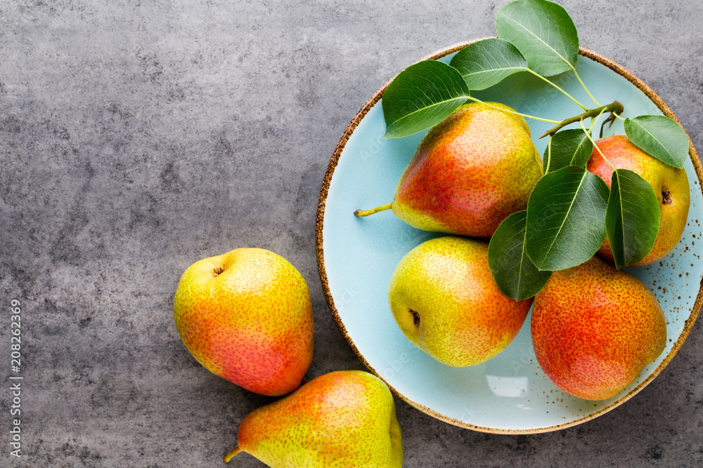 Fresh bio pear with leaves on the plate. Gray stone table. Fresh bio pear with leaves on the plate. Gray stone table.