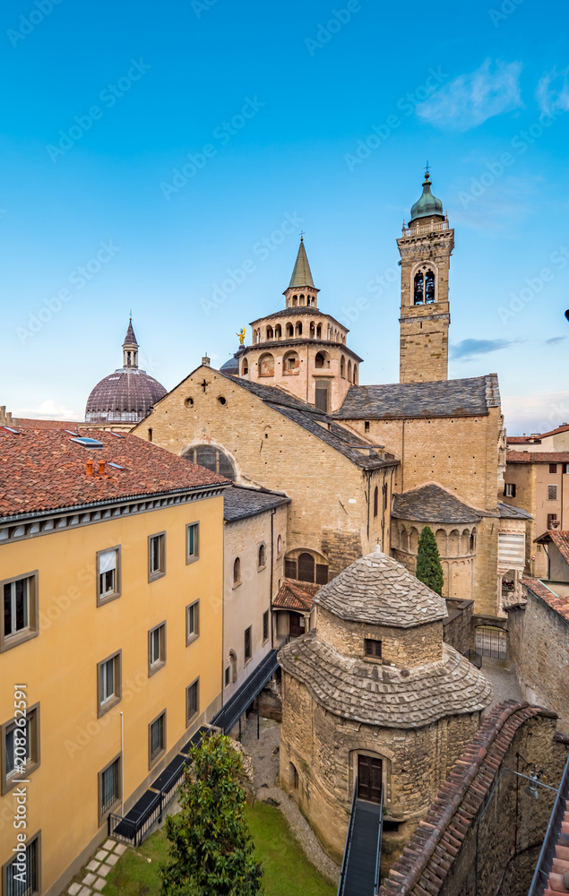 View of the Basilica of Santa Maria Maggiore and Cappella Colleoni in Citta Alta of Bergamo, Italy between narrow streets