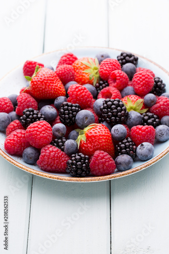 Fresh berry salad on blue dishes. Vintage wooden background.