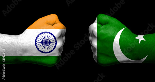 Flags of India and Pakistan painted on two clenched fists facing each other on black background/India - Pakistan relations concept photo