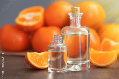 Bottles of citrus essential oil and fruit on table