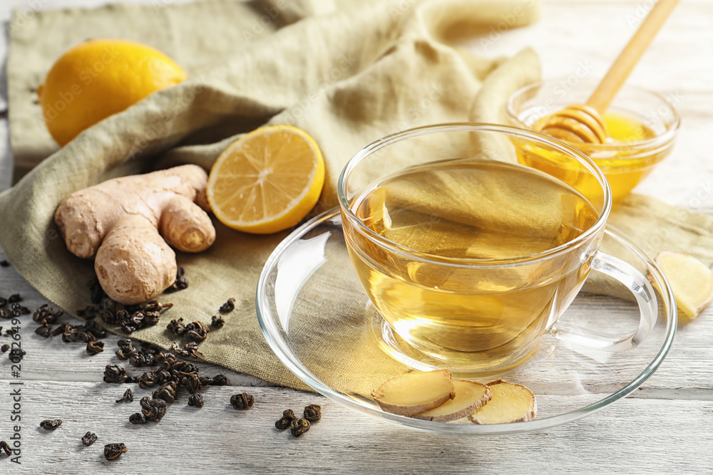 Cup of delicious tea with lemon, ginger and honey on table Cup of delicious tea with lemon, ginger and honey on table