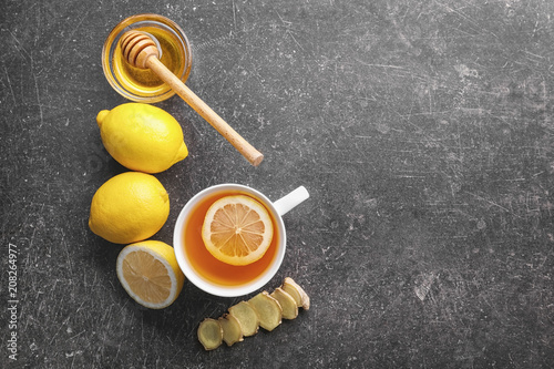 Delicious tea with honey, lemon and ginger on grey background