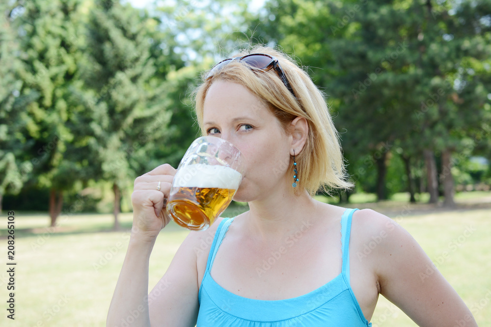 Portrait of happy woman holding glass of beer outside on sunny day. Portrait of happy woman holding glass of beer outside on sunny day.