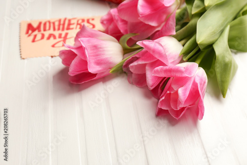 Beautiful tulips and handmade card for Mother's Day on white wooden background