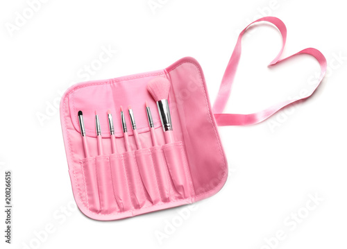 Set of makeup brushes in pink case on white background