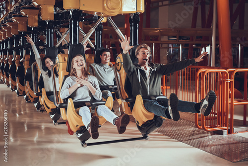 Friends ride on swing in amusement park.