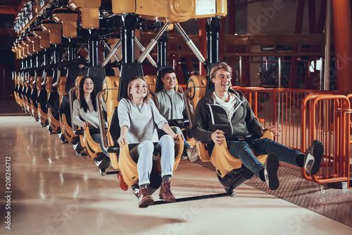 Obraz na plátně Happy young people ride on attractions.