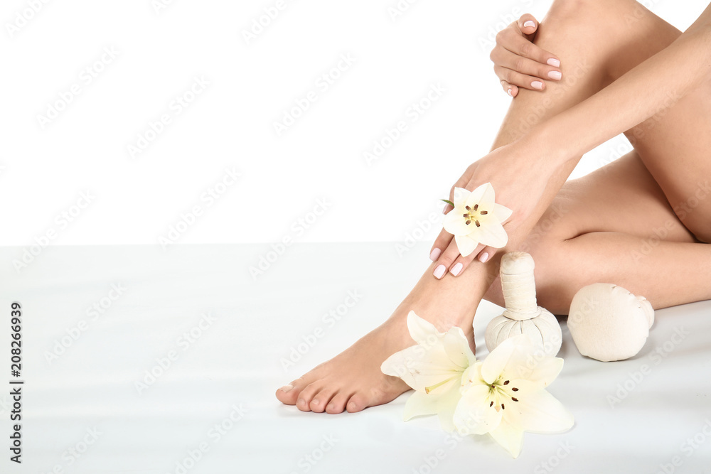 Young woman with flowers and herbal bags sitting on white background. Spa treatment Young woman with flowers and herbal bags sitting on white background. Spa treatment