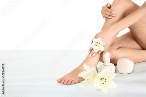 Young woman with flowers and herbal bags sitting on white background. Spa treatment
