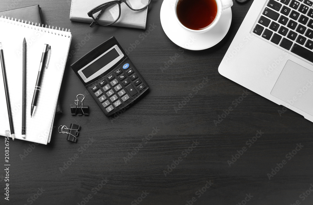 Laptop, cup of coffee and stationery on dark background, flat lay. Workplace table composition Laptop, cup of coffee and stationery on dark background, flat lay. Workplace table composition