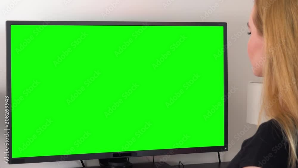 A woman sits at a desk and looks at a green computer screen - closeup from behind A woman sits at a desk and looks at a green computer screen - closeup from behind