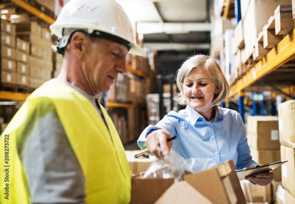 Senior woman manager and man worker working in a warehouse. Senior woman manager and man worker working in a warehouse.