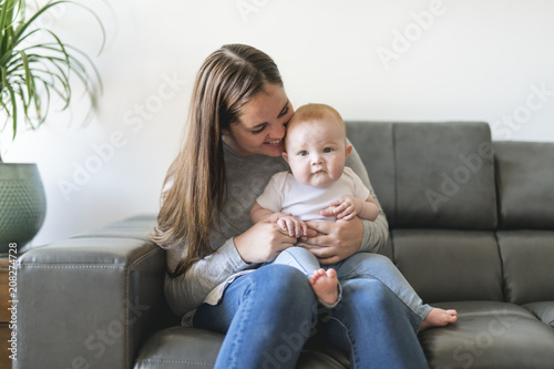 mother with baby daughter on sofa at home