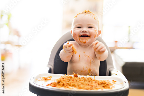 Little baby girl eating her spaghetti dinner and making a mess