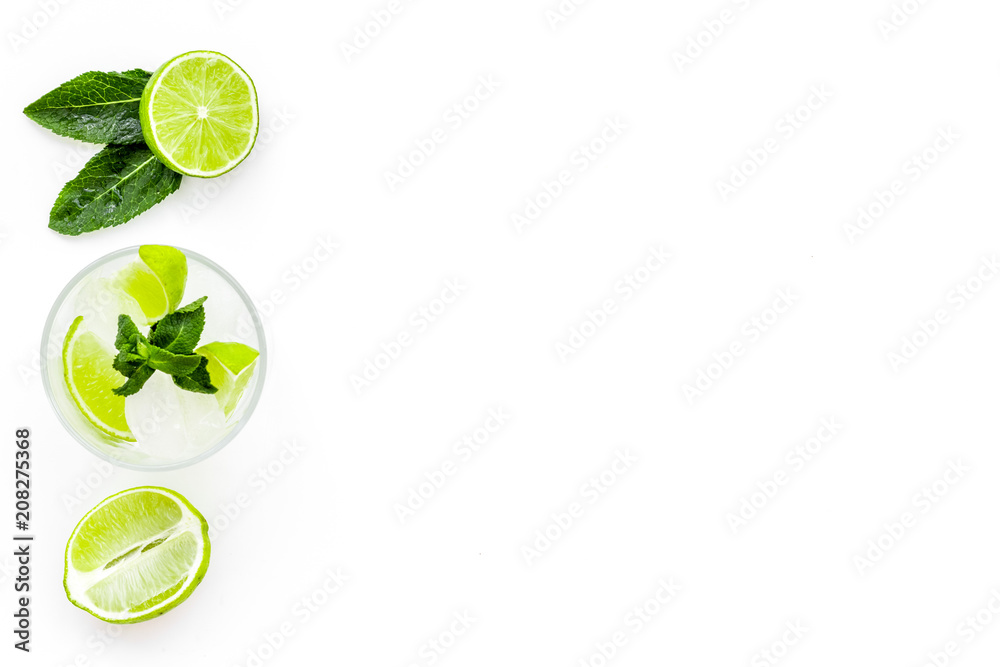 Refreshing mojito cocktail. Slices of lime, mint, glass with ice cubes on white background top view space for text