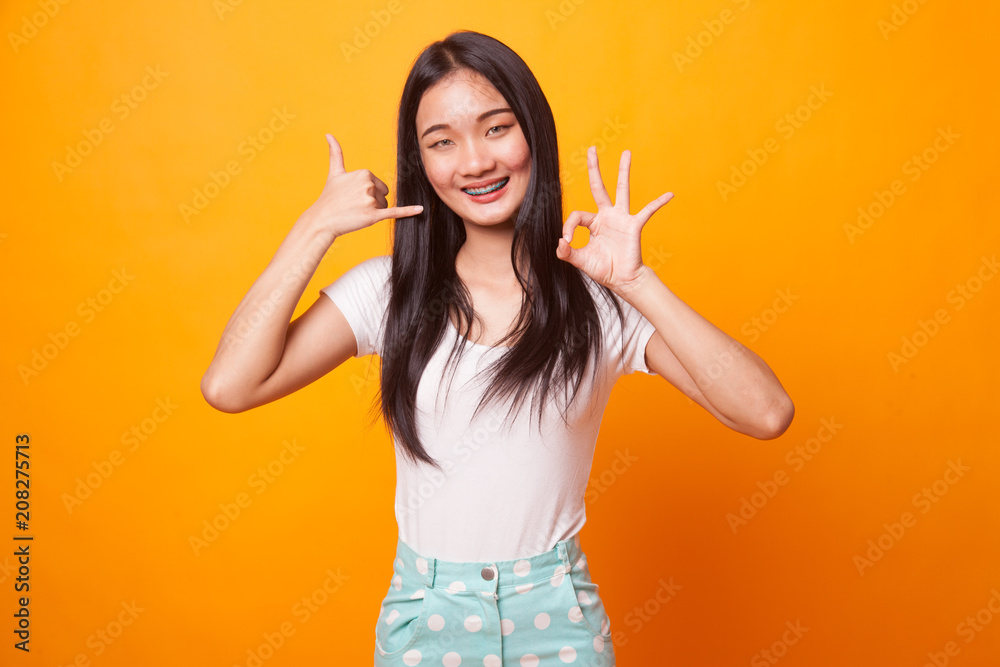 Young Asian woman show with phone gesture and OK sign. Young Asian woman show with phone gesture and OK sign.