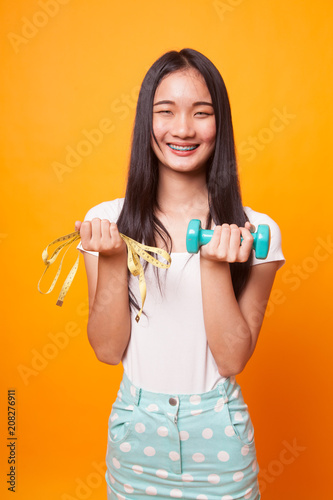 Healthy Asian woman with dumbbells and measuring tape.