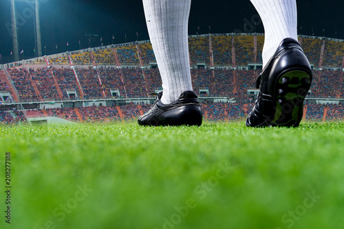 Foot of soccer player or football player walk on green grass ready to play match for the winner with stadium backgrounds.