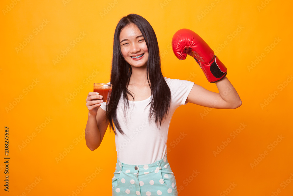 Young Asian woman with tomato juice and boxing glove. Young Asian woman with tomato juice and boxing glove.