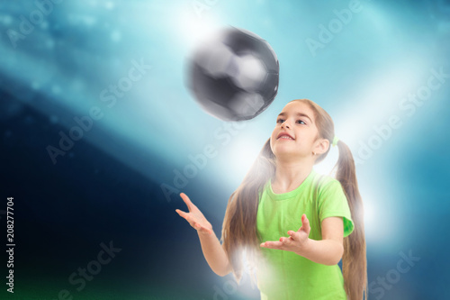 Cheerful little girl plays with soccer ball