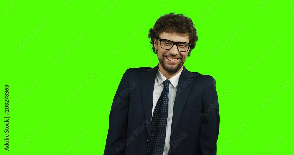 Portrait shot of the handsome Caucasian man in the glasses, suit and tie laughing cheerfully while standing on the chroma key background. Green screen. Portrait shot of the handsome Caucasian man in the glasses, suit and tie laughing cheerfully while standing on the chroma key background. Green screen.