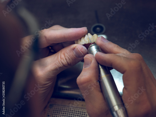 Technician carving teeth on denture photo