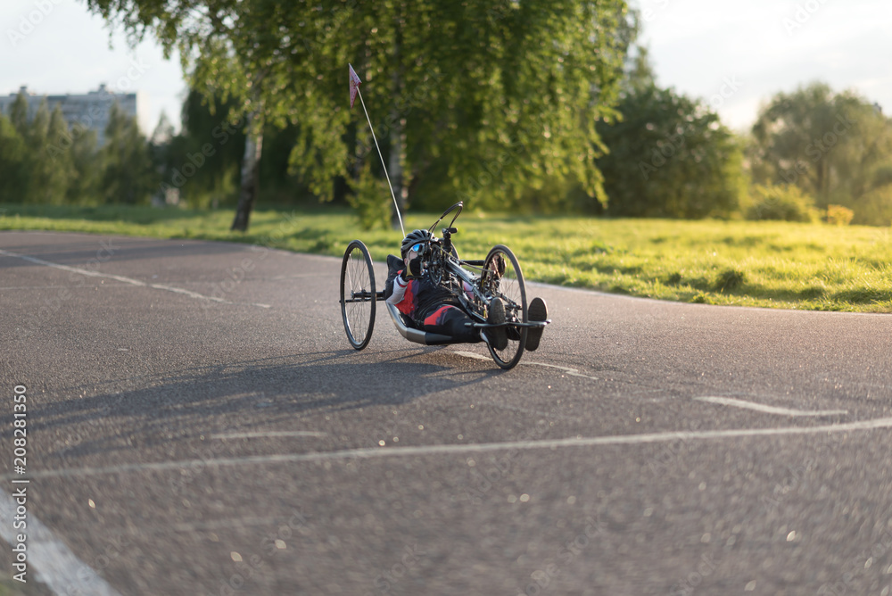 Obraz premium A close up of the handbike athlete on the special bicycle asphalt track in Krylatskie Hills. Evening sunset above the road.