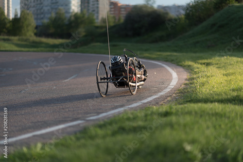 A close up of the handbike athlete on the special bicycle asphalt track in Krylatskie Hills. Evening sunset above the road.