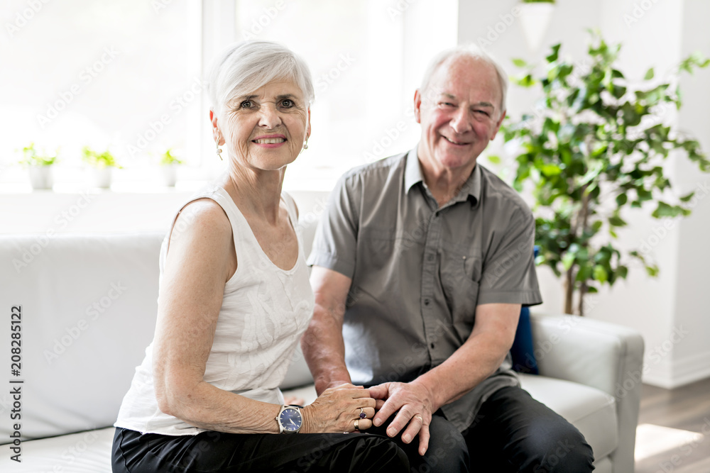 Affectionate attractive elderly couple sitting together on a couch
