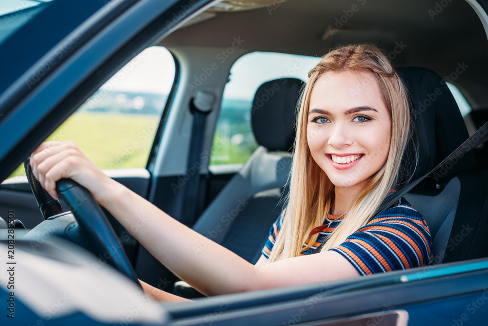 close up shot of smiling young woman sitting behind car wheel close up shot of smiling young woman sitting behind car wheel