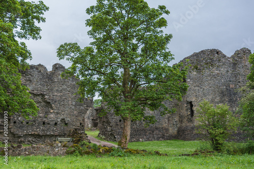 Torlundy, Scotland - June 11, 2012: Outside wall with breach of Inverlochy Castle under gray skies. Green trees and lawn up front. View unto castle courtyard. photo