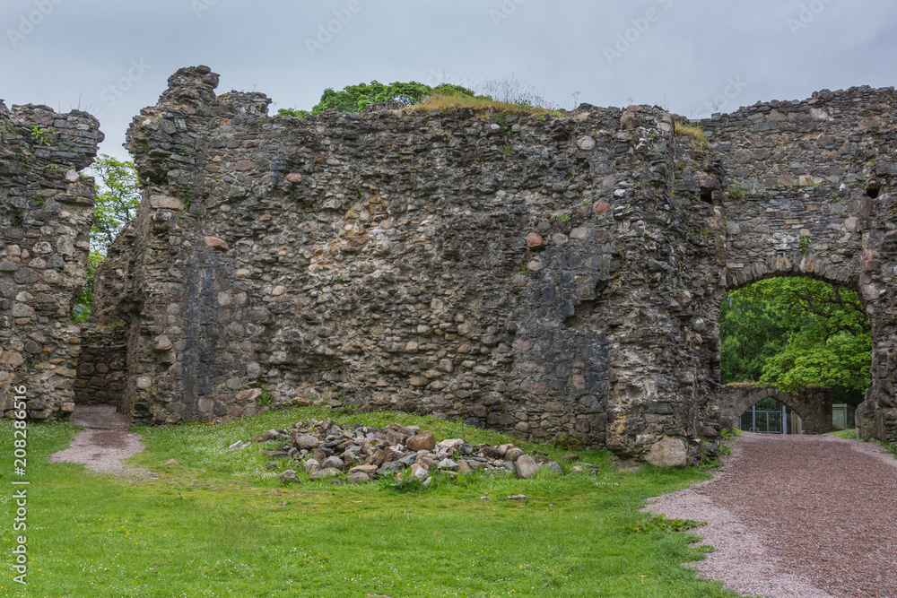 Torlundy, Scotland - June 11, 2012: One wide and one narrow Pass-through openings in defensive wall inside Inverlochy Castle. Green trees and other gate showing in frame of natural stones.