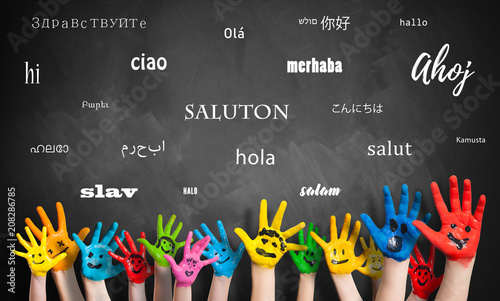 Viele Kinderhände vor Wandtafel mit dem Wort "Hallo" in vielen Sprachen 
